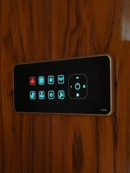 A close-up of a smart panel with custom icons, installed on a rich, wooden surface in a client's villa.
