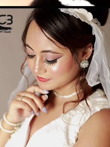 A close-up portrait of a model in a classic white bridal gown and veil, showcasing a soft and elegant makeup look.