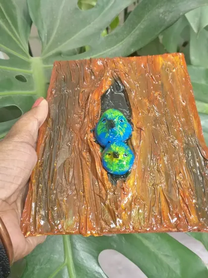 A small, abstract painting of two lovebirds nestled in a tree trunk. This piece uses thick texture to create a rustic, 3D effect.