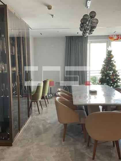The dining area of the DLF Belaire project, featuring a large marble table and a stunning floor-to-ceiling glass wine and crockery display cabinet.