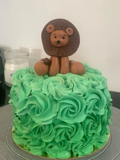 A simple yet regal first birthday cake. This cake features green buttercream rosettes topped with a handmade fondant lion.