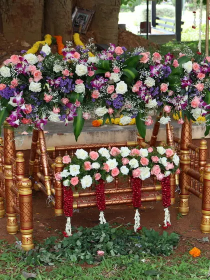 For outdoor naming ceremonies, I provide this traditional wooden cradle, or thottilu, heavily decorated with fresh, multi-colored flowers for a beautiful natural setting.
