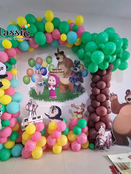 A Masha and the Bear themed party with a custom backdrop showing all the characters, a balloon arch, and a tree made of balloons.