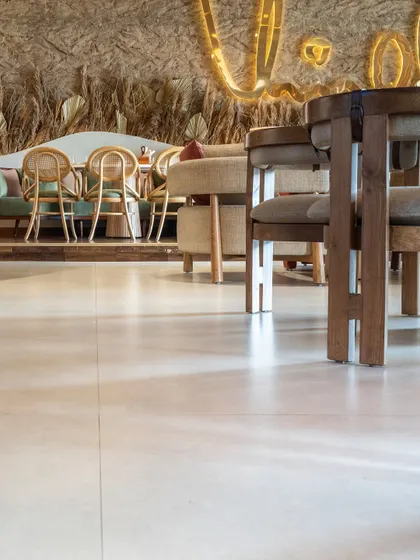 A low-angle shot of the flooring at One 8 Commune. The smooth, seamless finish of the large-format tiles provides a clean and modern foundation that complements the rustic and textured elements of the restaurant's decor.