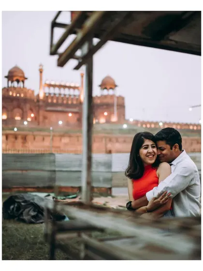 A warm embrace with the iconic Red Fort in the background. This photo blends a personal, loving moment with a landmark of Delhi.