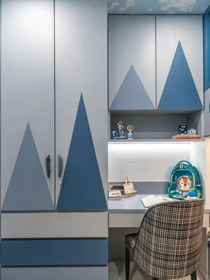 Here, you can see the custom wardrobe and drawers, decorated with a mountain motif in shades of blue. The design provides ample storage for clothes and toys while tying into the room's adventurous theme.
