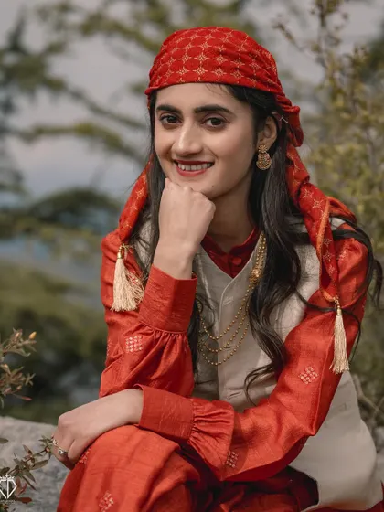 A lovely close-up portrait of the woman in her red traditional Himachali outfit, her smile radiating pure joy and contentment.