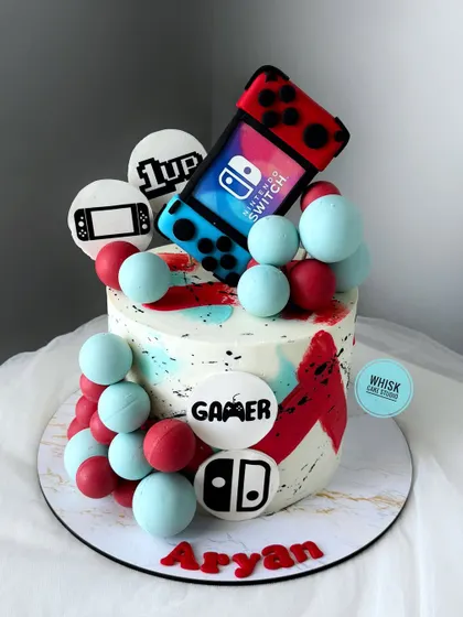 A fun and colorful cake for a gamer. This design is themed around the Nintendo Switch, with edible controllers and game icons decorating the cake.