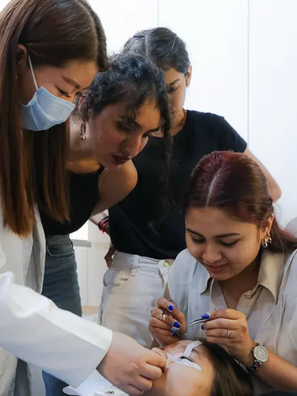 Learning is a team sport here. Students gather to observe and learn from each other as an instructor provides detailed guidance during a live model practice session.