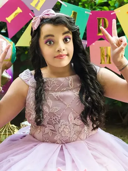 The birthday girl flashes peace signs, full of personality and fun during her colorful outdoor party.