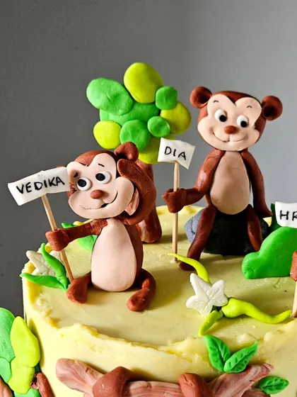 A close-up of the "Five Little Monkeys" cake toppers. Each monkey holds a sign with a child's name, making it a very personal and fun cake for the family.