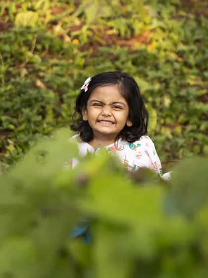 A cheeky smile while peeking through the leaves. These playful moments are what make milestone sessions so much fun, capturing the true personality of your child.