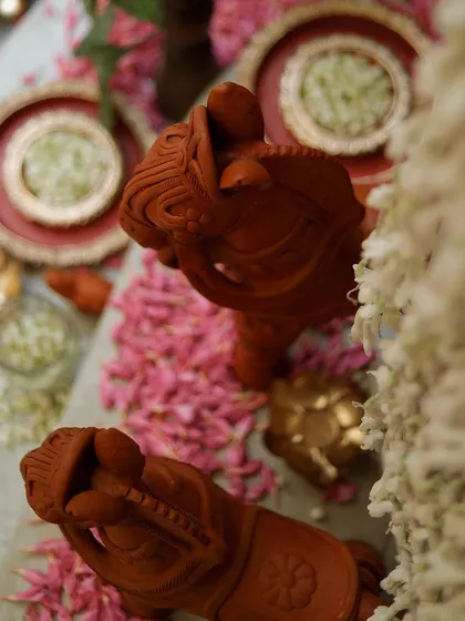 A detailed overhead view of the terracotta horse figurines, surrounded by a carpet of pink petals. This shot captures the artistry and traditional aesthetic of the event.