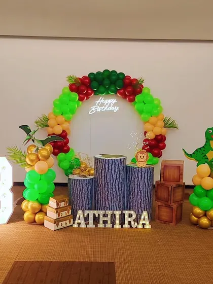 A simple and fun dinosaur-themed birthday party. The circular balloon arch is accented with tropical leaves and a T-Rex cutout for a prehistoric adventure.