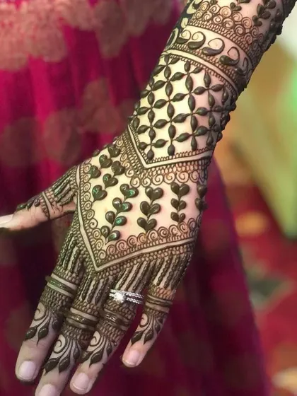 A beautiful back-of-hand design featuring a V-shaped pattern of heart-filled vines. The top of the hand is covered in a classic 'jaal' net pattern, perfect for an engagement.