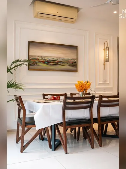 A classic contemporary dining room designed to feel light, airy, and special. Sleek wall mouldings and bright white walls are complemented by a dark wood dining set and elegant wall sconces for a touch of warmth.