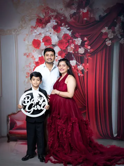A full family maternity portrait, with the older brother proudly holding a 'Baby Girl' sign, celebrating the upcoming arrival.