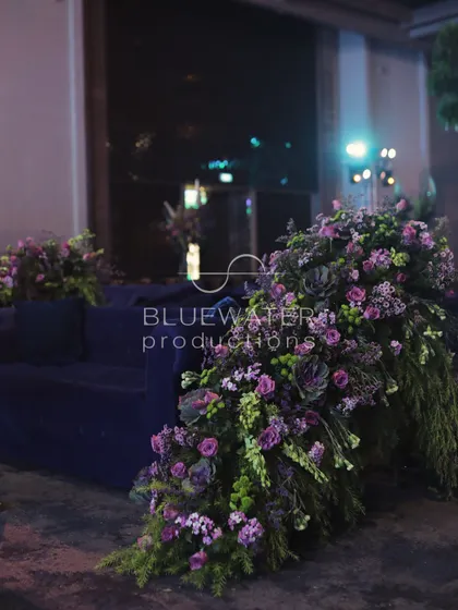 A lush floral arrangement spills over the side of a deep blue velvet sofa in the Sangeet lounge.