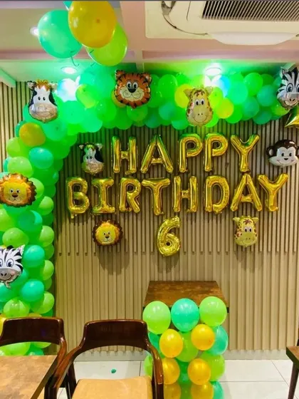 A classic jungle theme birthday setup, perfect for a 6th birthday. This decoration uses a green and yellow balloon arch with animal head foil balloons to create a simple yet effective jungle vibe.
