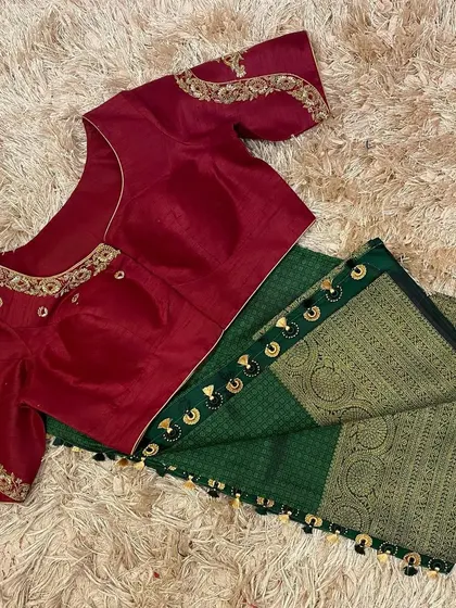 A rich maroon blouse with gold embroidery, paired with a dark green silk saree for a royal look.