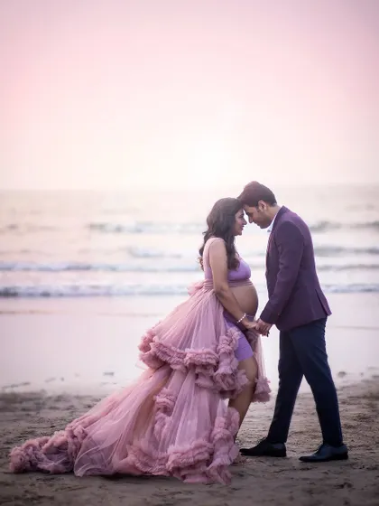 An intimate moment between an expecting couple on the beach. The soft focus on the waves and the gentle light create a dreamy, romantic atmosphere for this maternity portrait.