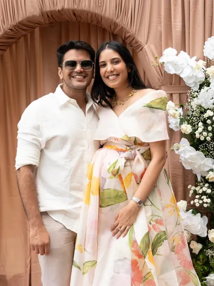 The happy parents-to-be pose in front of the sophisticated "Mocha Mousse" themed backdrop, a perfect picture of love and anticipation.