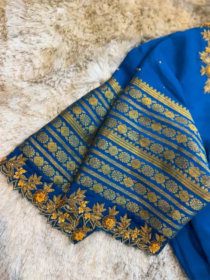 A close-up of the sleeve of the blue blouse, combining a traditional woven border with custom floral embroidery.