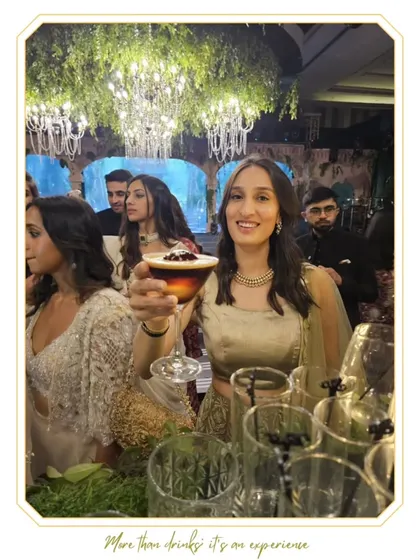 A guest holds up her elegant coupe cocktail at a sophisticated event. Our drinks are designed to match the glamour of any occasion.