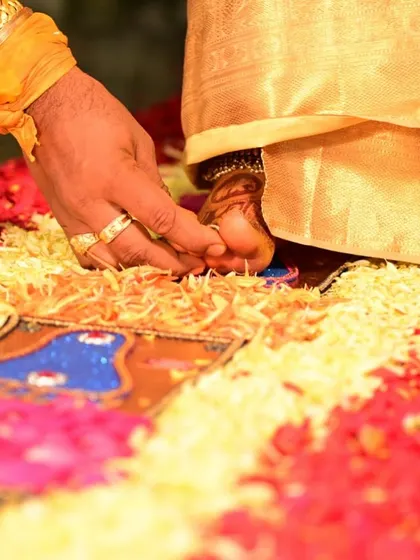 A close-up of the 'Saptapadi' or seven steps ritual, showing the groom guiding the bride's foot, beautifully decorated with henna.
