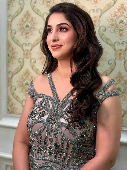 A side view of this elegant look, showing the soft waves in her hair and the flawless, radiant finish of the makeup.