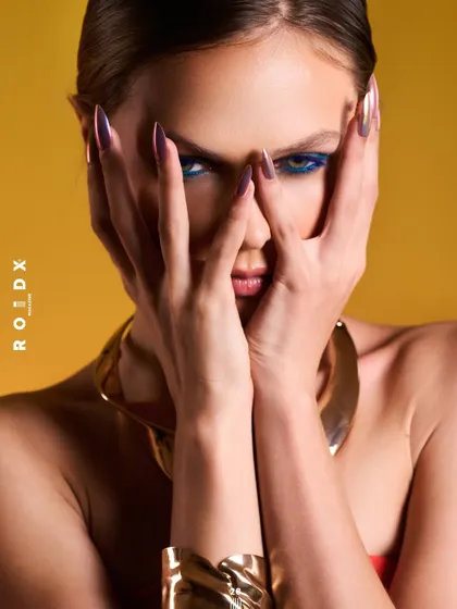 A beauty-focused shot for Roidx Magazine. The composition is tight and confrontational, with bold makeup and sharp lighting.