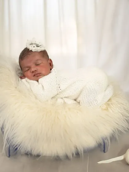 In the calm of her slumber, we see the magic of pure peace. This angelic shot features a baby sleeping on a fluffy fur-lined crescent moon prop, with a tiny puppy figure nearby.