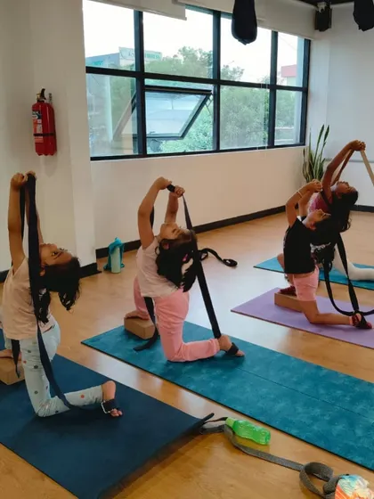 Using yoga straps to deepen the stretch in a modified King Pigeon Pose. Props help our young students achieve poses safely and effectively, enhancing their flexibility.