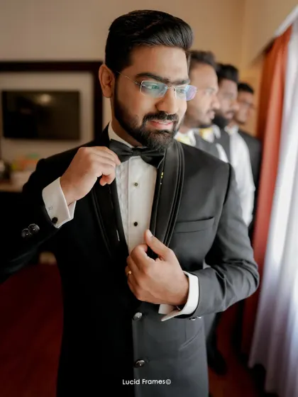 The groom, looking sharp in his tuxedo, with his groomsmen lined up behind him.