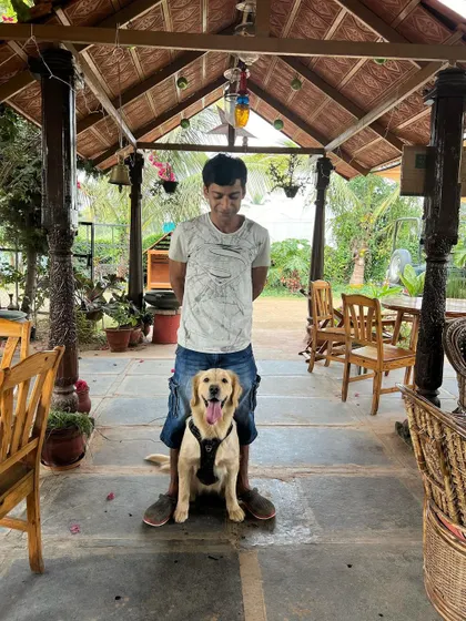 A guest and his dog pose for a photo inside our cafe area, with the rustic wooden chairs and pillars visible in the background.