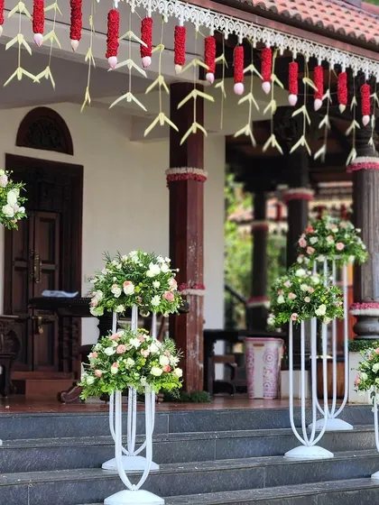 The entrance to this traditional home is lined with elegant floral stands. The arrangements of white and pink roses create a welcoming path for guests, showcasing our commitment to quality and detail at every step.