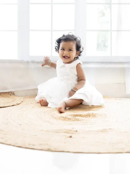 A solo portrait of the adorable baby girl from the family session, smiling happily.