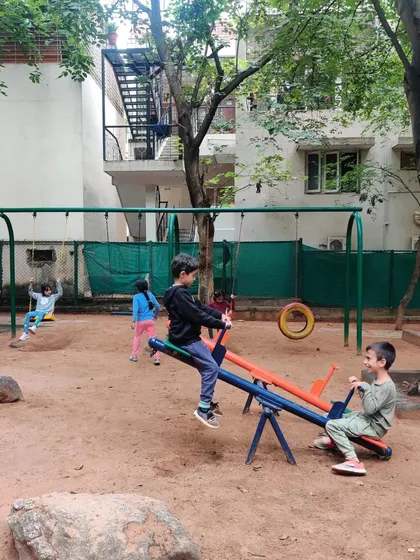 Two boys work together to make the see-saw go, learning about balance, cooperation, and physics through play.