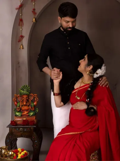 A classic seated portrait of the couple, with the Ganesha idol in the background adding a spiritual and auspicious element to their maternity photo.