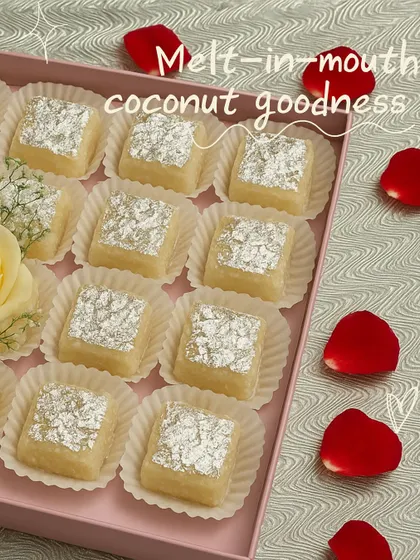 A box of our Nariyal ki Chakki, showcasing its delicate, melt-in-mouth coconut goodness. Each piece is perfectly square and adorned with edible silver leaf, making it a beautiful gift.