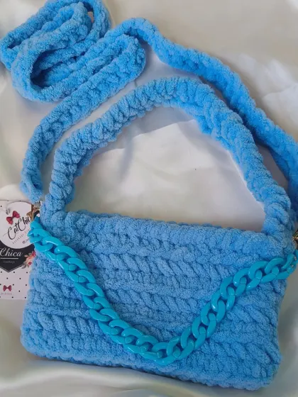 A beautiful sky blue crochet baguette bag, featuring a matching blue plastic chain detail.