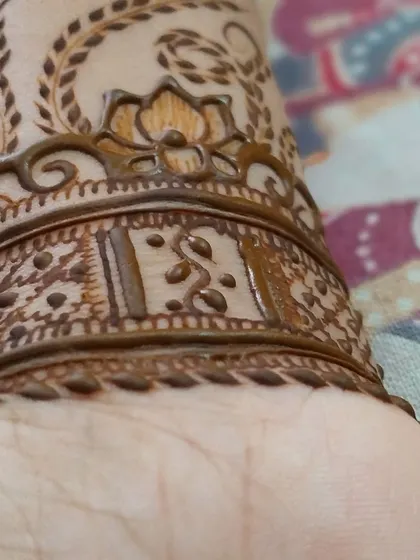 A custom armband design with initials hidden inside. This is a unique way to personalize your mehandi for any event.
