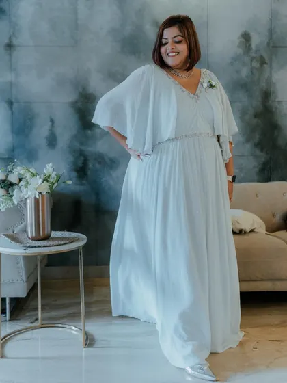 A solo shot of the beautiful custom-wear gown in a soft pastel blue. The design features a delicate V-neck and fluttery cape sleeves for an ethereal look.