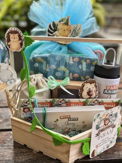 A jungle-themed birthday hamper for a little boy, presented in a wooden basket and adorned with a custom vine detail and cute animal cutouts.
