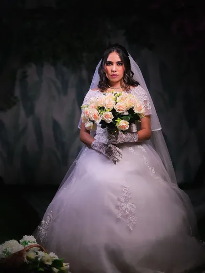 A classic Christian bride look, featuring a beautiful white ball gown, veil, and a bouquet of roses.