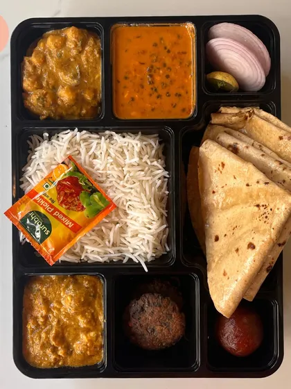 Take a look at our premium North Indian meal box. This thali features multiple vegetable preparations, dal makhani, fluffy basmati rice, soft rotis, a kebab, and a gulab jamun for dessert. It's a complete, wholesome meal packed hygienically for any occasion.
