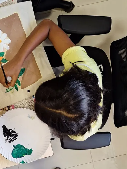 An overhead shot of a young artist painting her floral tote bag. It's a great angle to see the artwork taking shape.
