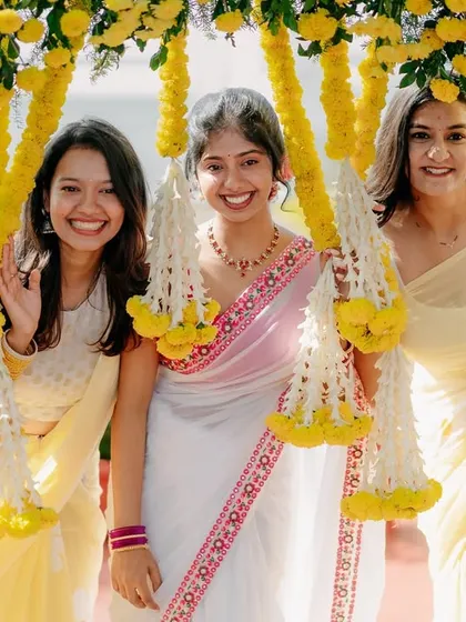 Friends pose for a photo under a bright yellow floral arch, capturing the fun and vibrant spirit of the Haldi event.