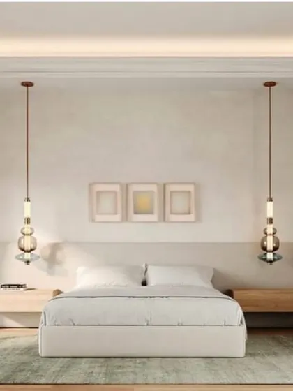 Two Luna Kaleido pendants flank a bed, offering a symmetrical and sophisticated alternative to traditional bedside lamps. Their vertical form draws the eye upwards.