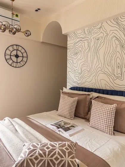 A full view of this imaginative kids' room, showing the bed with its unique topographic map wallpaper, a large wall clock, and a balcony that lets in plenty of natural light.